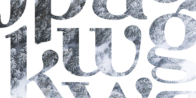 Milk Drops Font. Curves of letterforms highlighted against a chilly aerial forest view.